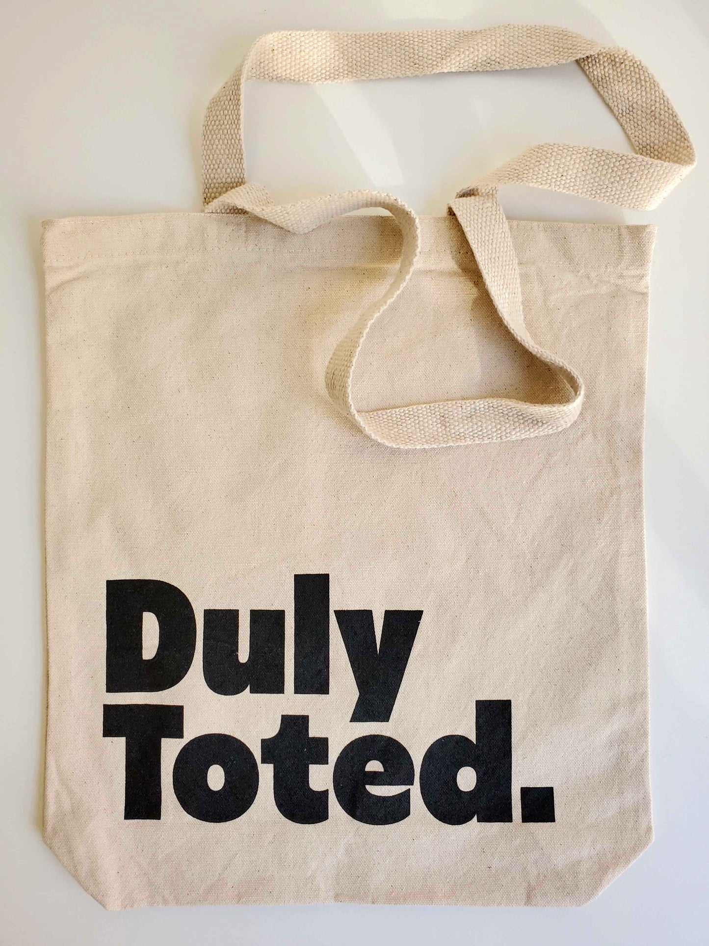 Natural Canvas tote with the words Duly Toted in chunky black font.