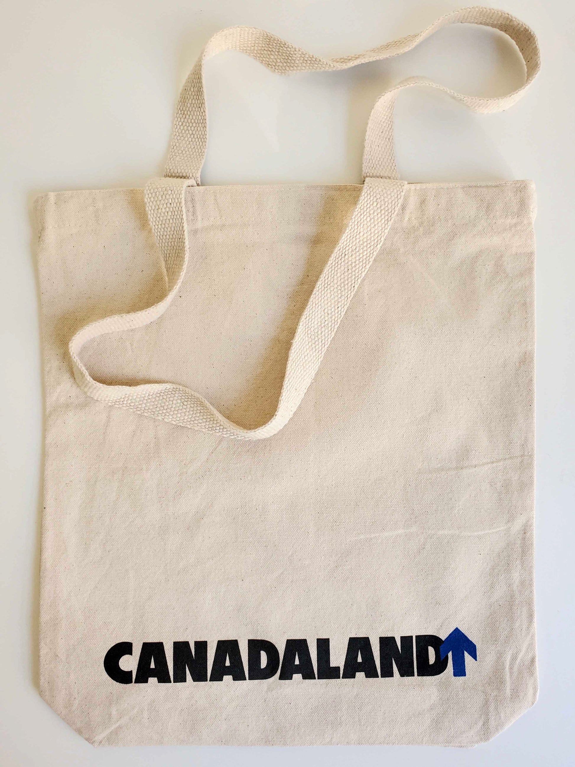 The back of the Duly Toted tote bag. The horizontal Canadaland logo in black and blue across the bottom.