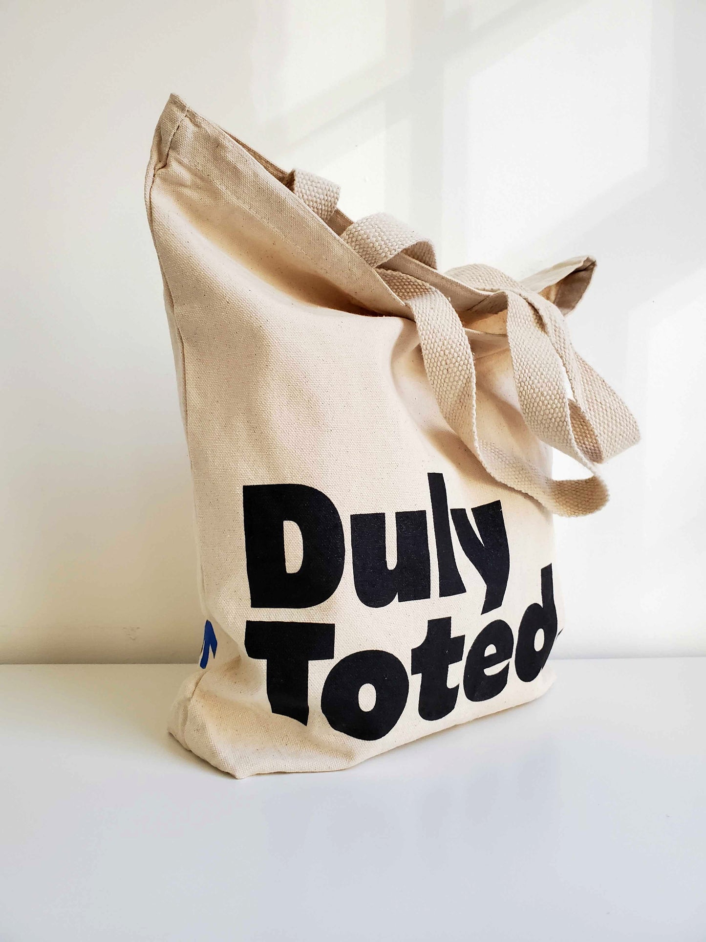 The Duly Toted tote bag standing upright.